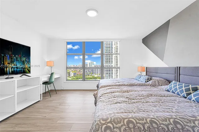 a bedroom with a large bed and a flat tv screen on dresser