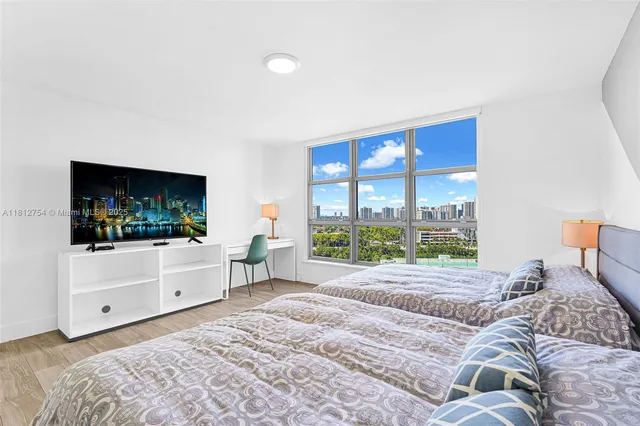 a bedroom with a large bed and a flat tv screen on dresser