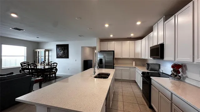 a kitchen with refrigerator a sink and chairs