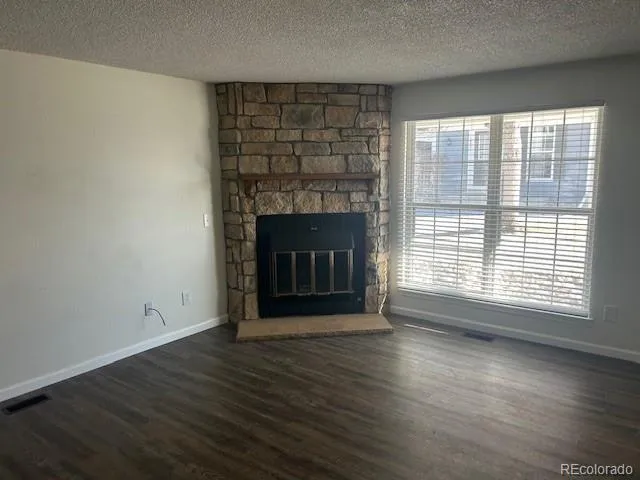 an empty room with wooden floor fireplace and windows