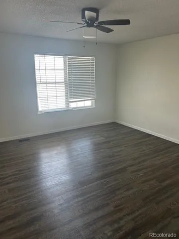 an empty room with wooden floor chandelier fan and windows