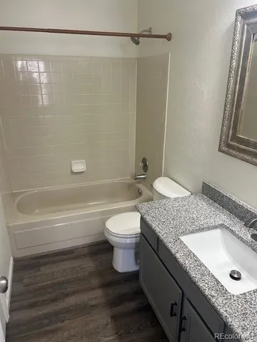 a bathroom with a granite countertop bathtub shower sink vanity and toilet