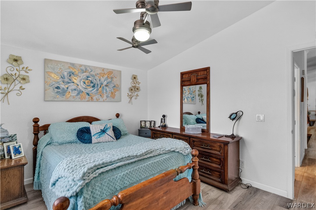 784 Pegasus Ranch Road Bullhead City, AZ 86429 - Photo 44 of 100 Bedroom featuring two ceiling fans with integrated lighting, wood-finish flooring, a white wall finish, and a doorway leading to an interior space