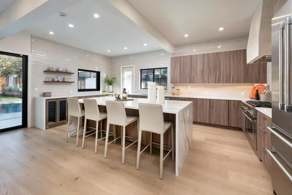a kitchen with stainless steel appliances kitchen island granite countertop a table chairs sink and cabinets