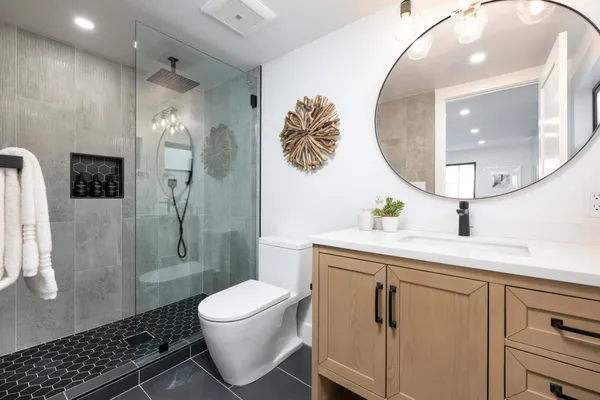a spacious bathroom with a granite countertop sink toilet a mirror and shower