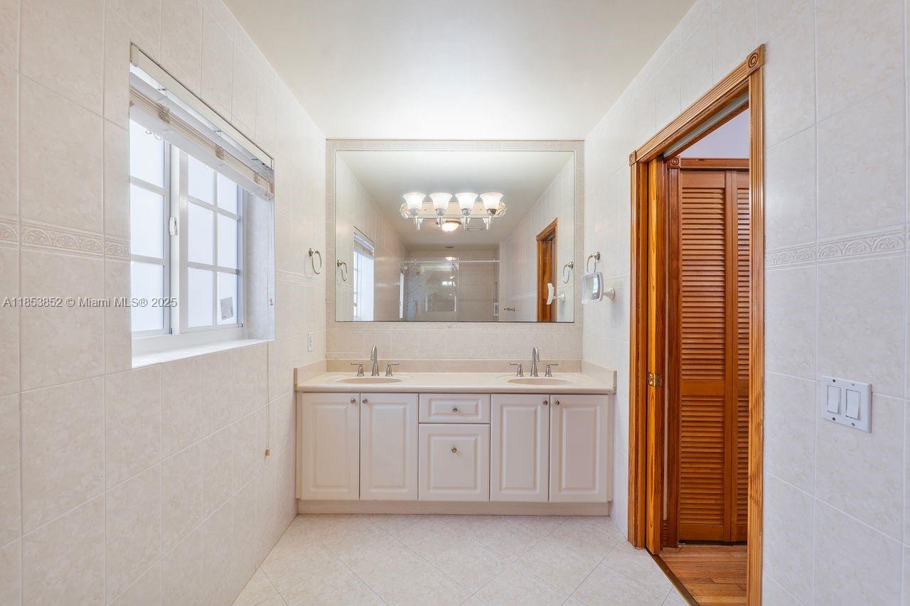 13000 Old Cutler Road Pinecrest, FL 33156 - Photo 19 of 43 a large bathroom with a double vanity sink a mirror and a bathtub