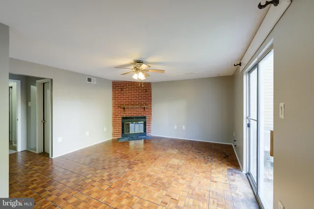an empty room with chandelier fan and windows