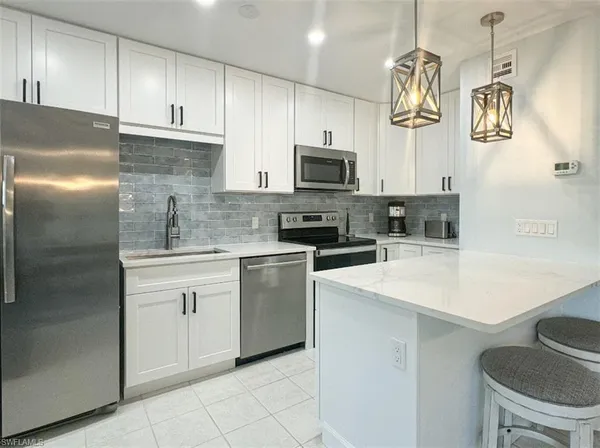 a kitchen with stainless steel appliances granite countertop a sink a stove a refrigerator cabinets and chairs