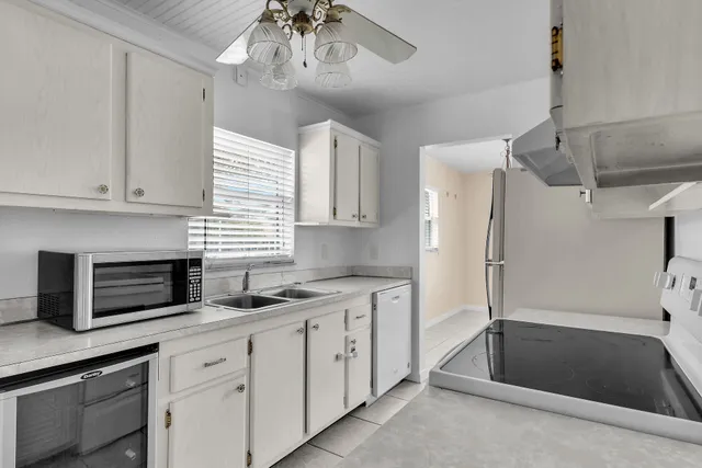a kitchen with stainless steel appliances kitchen island granite countertop a refrigerator a sink and white cabinets