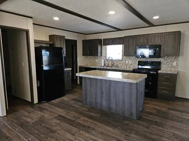 a kitchen with stainless steel appliances granite countertop a refrigerator a sink a stove a microwave and wooden cabinets