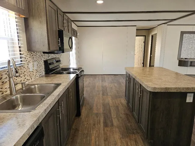 a kitchen with kitchen island granite countertop a sink a counter space and wooden floor