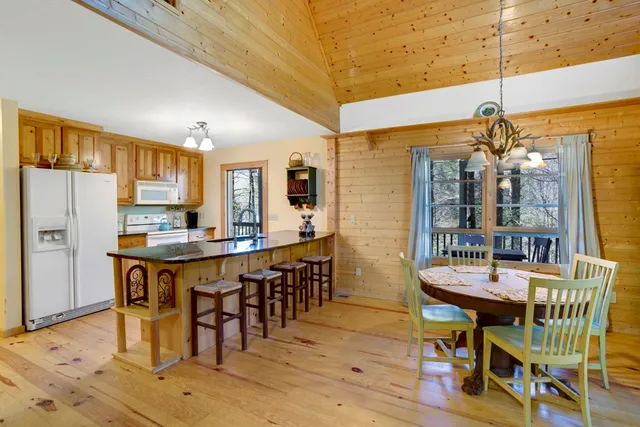 a dining room with stainless steel appliances a table chairs and a refrigerator
