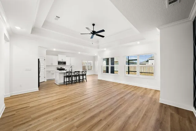 a view of an empty room with a window and wooden floor