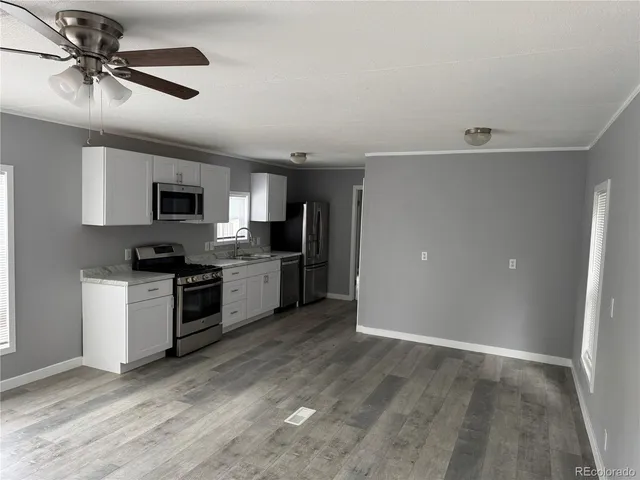 a kitchen with granite countertop a refrigerator a sink a stove a microwave and cabinets