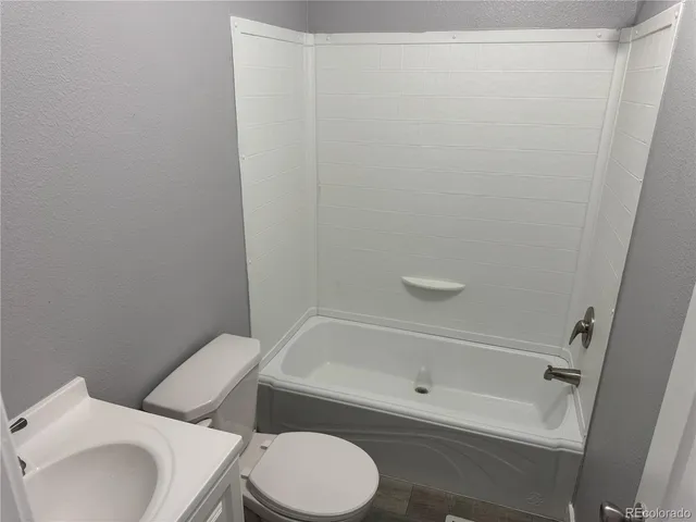 a white toilet sitting next to a bath tub