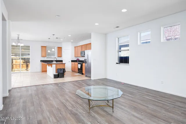 a living room with stainless steel appliances kitchen island hardwood floor and a kitchen view