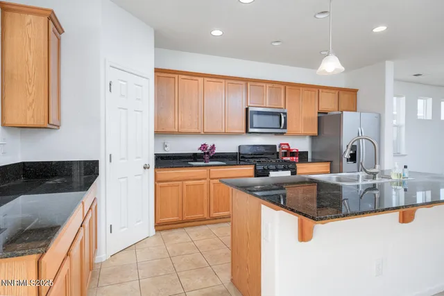 a kitchen with granite countertop a sink a counter top space appliances and cabinets