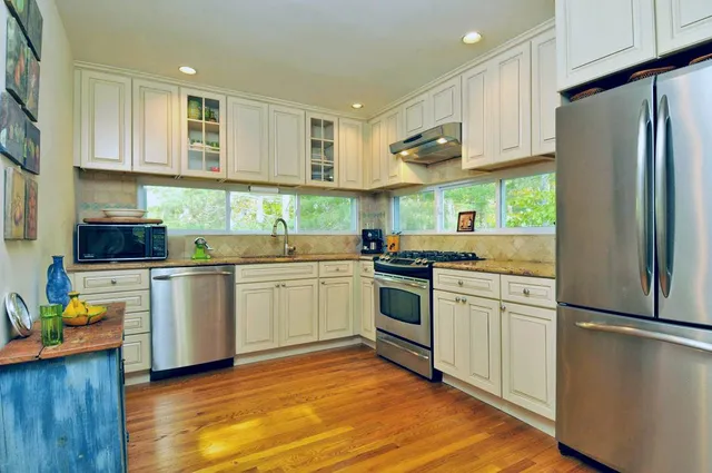 a kitchen with a sink cabinets stainless steel appliances and wooden floor