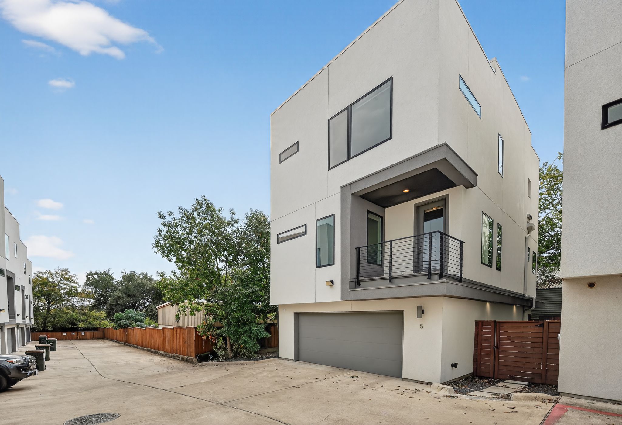View of front facade featuring stucco siding, a balcony, and concrete driveway