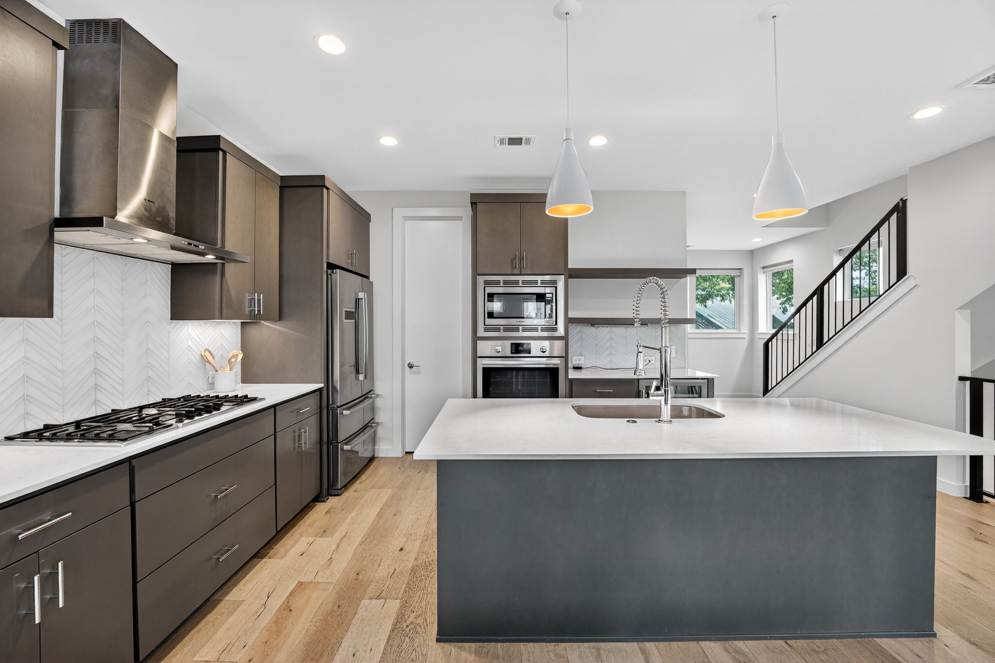 2301 Bluebonnet Lane, Unit 5 Austin, TX 78704 - Photo 13 of 26 Kitchen featuring modern cabinets, wall chimney range hood, appliances with stainless steel finishes, pendant lighting, and decorative backsplash