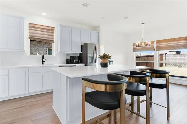 a kitchen with stainless steel appliances a dining table chairs stove and sink