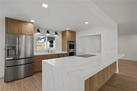 a large kitchen with a large counter top kitchen island a sink a refrigerator and a counter top space
