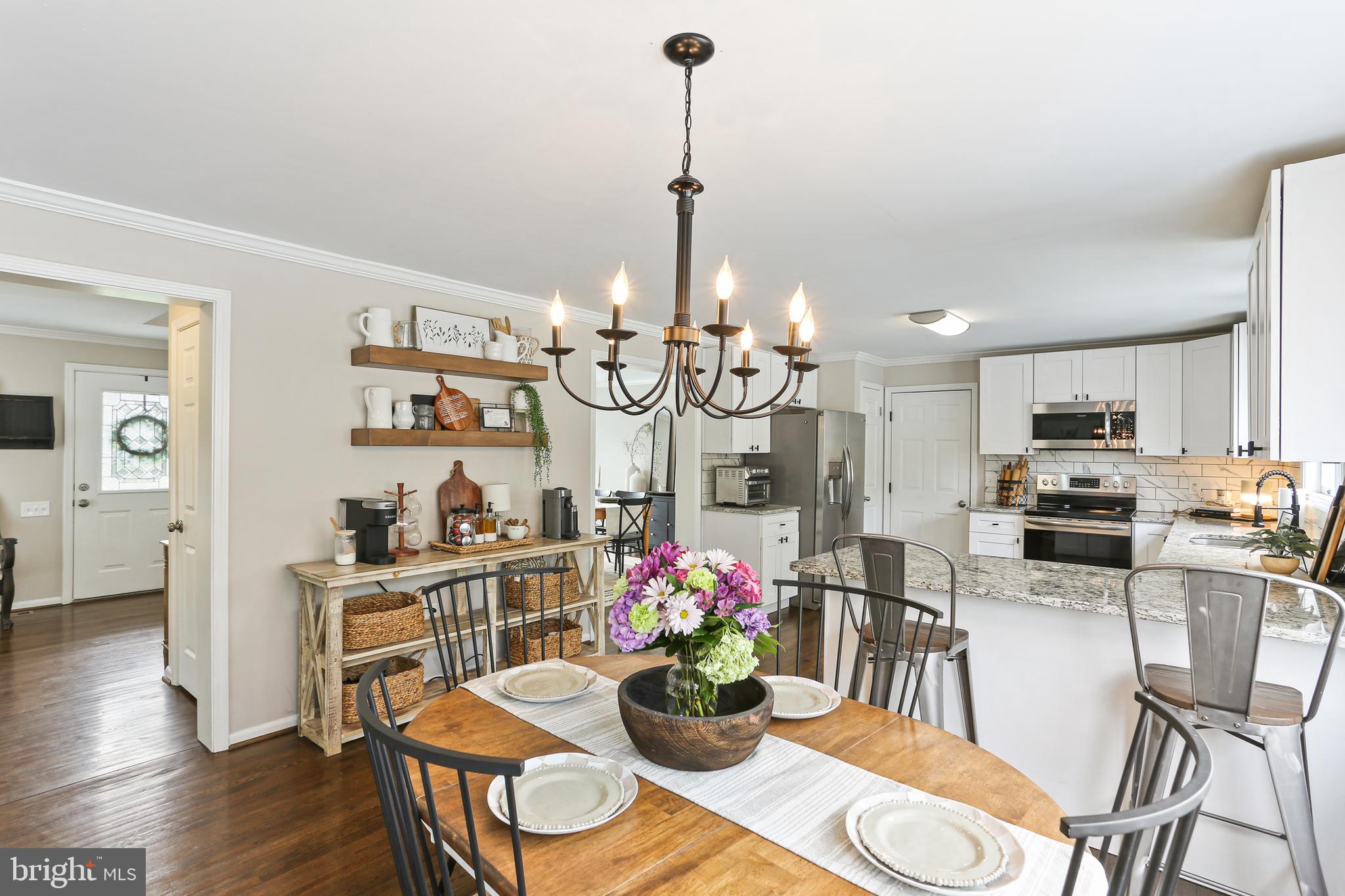 3234 Bidle Road Middletown, MD 21769 - Photo 11 of 45 a kitchen with stainless steel appliances kitchen island granite countertop a dining table chairs and white cabinets
