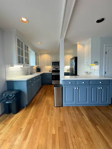 a large kitchen with wooden floors and stainless steel appliances