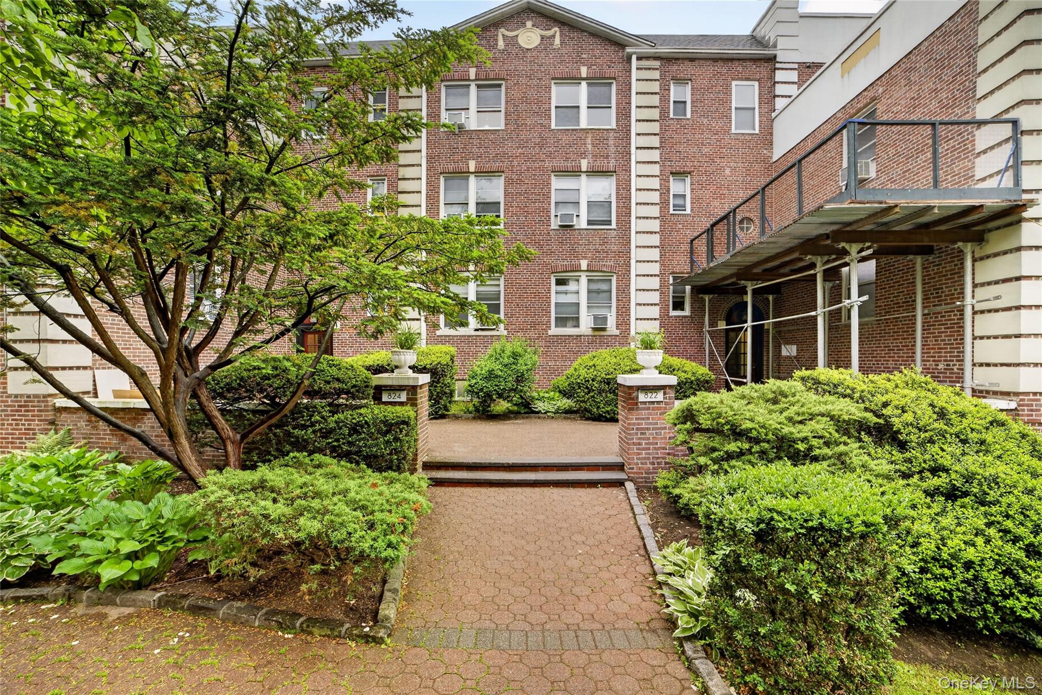 824 Palmer Road, Unit 1F Bronxville, NY 10708 - Photo 1 of 26 a view of a brick house with a yard and plants