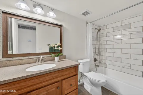 a bathroom with a granite countertop sink toilet a mirror a vanity and shower