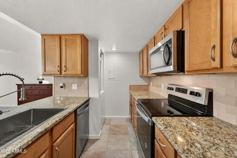 a kitchen with stainless steel appliances granite countertop a sink stove and refrigerator