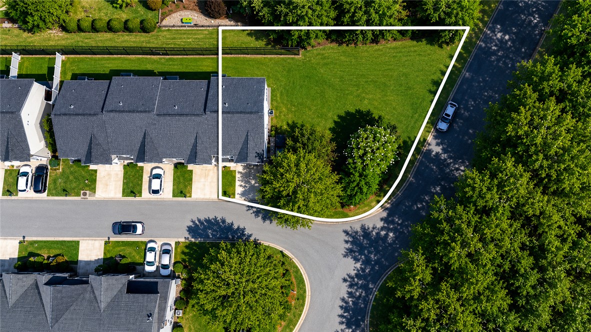 102 Ventura Street Anderson, SC 29621 - Photo 2 of 24 A well-maintained green yard with mature trees offers a tranquil setting adjacent to a paved road.
