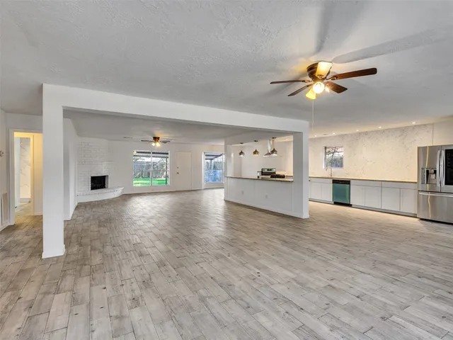 a large kitchen with stainless steel appliances a refrigerator a stove a sink dishwasher a oven with wooden floor and cabinets