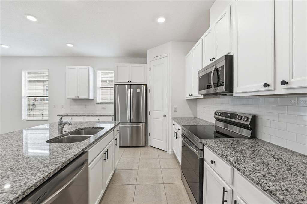 6550 Barnstorm Way St. Cloud, FL 34771 - Photo 16 of 35 a kitchen with stainless steel appliances granite countertop a sink stove and refrigerator