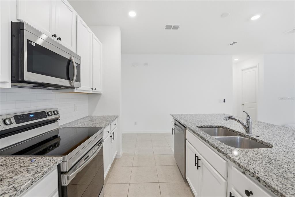 6550 Barnstorm Way St. Cloud, FL 34771 - Photo 17 of 35 a kitchen with granite countertop a sink and stainless steel appliances