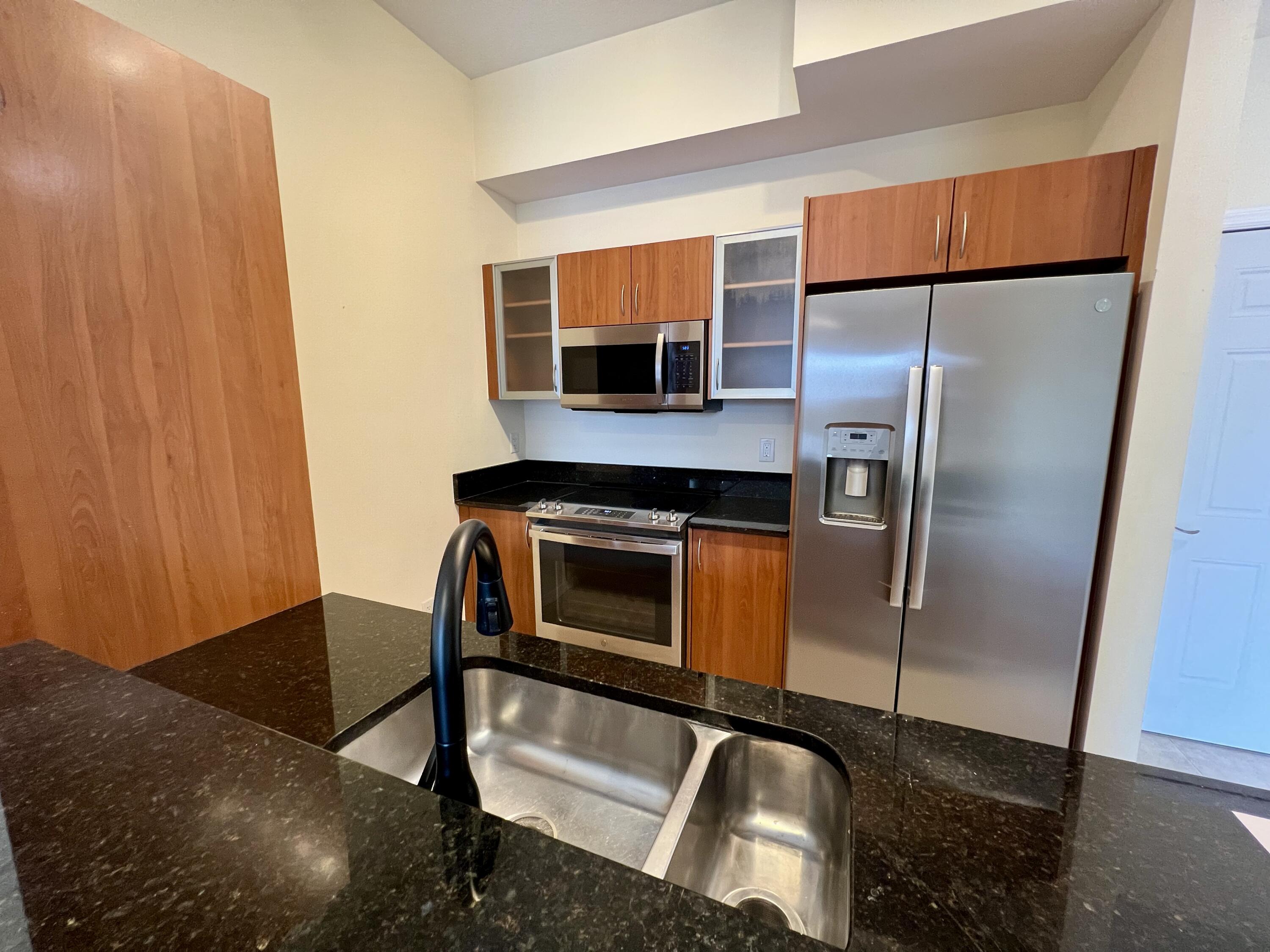 233 South Federal Highway, Unit UPH04 Boca Raton, FL 33432 - Photo 3 of 26 a kitchen with stainless steel appliances granite countertop a refrigerator a stove and a sink with wooden floor