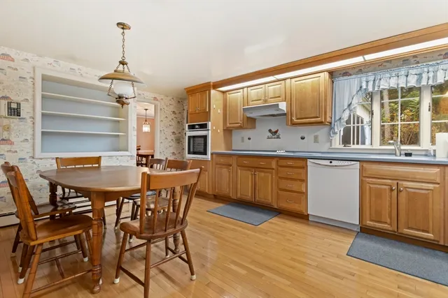a dining hall with stainless steel appliances kitchen island granite countertop a sink table and chairs