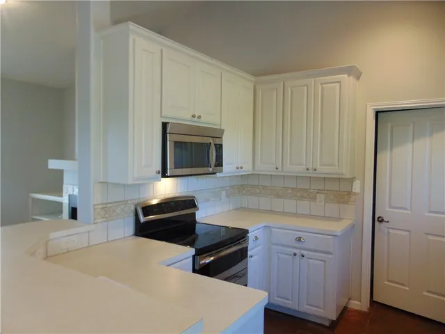 a kitchen with granite countertop white cabinets and stainless steel appliances