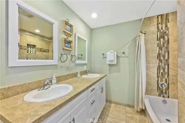 a bathroom with a granite countertop double vanity sink mirror double and shower