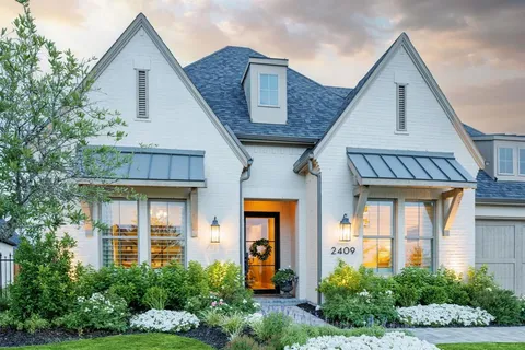 a front view of a house with glass windows and plants