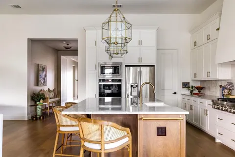 a kitchen with stainless steel appliances granite countertop a stove a sink dishwasher a dining table and chairs with wooden floor