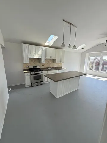 a kitchen with stainless steel appliances a stove top oven a sink a window and white cabinets