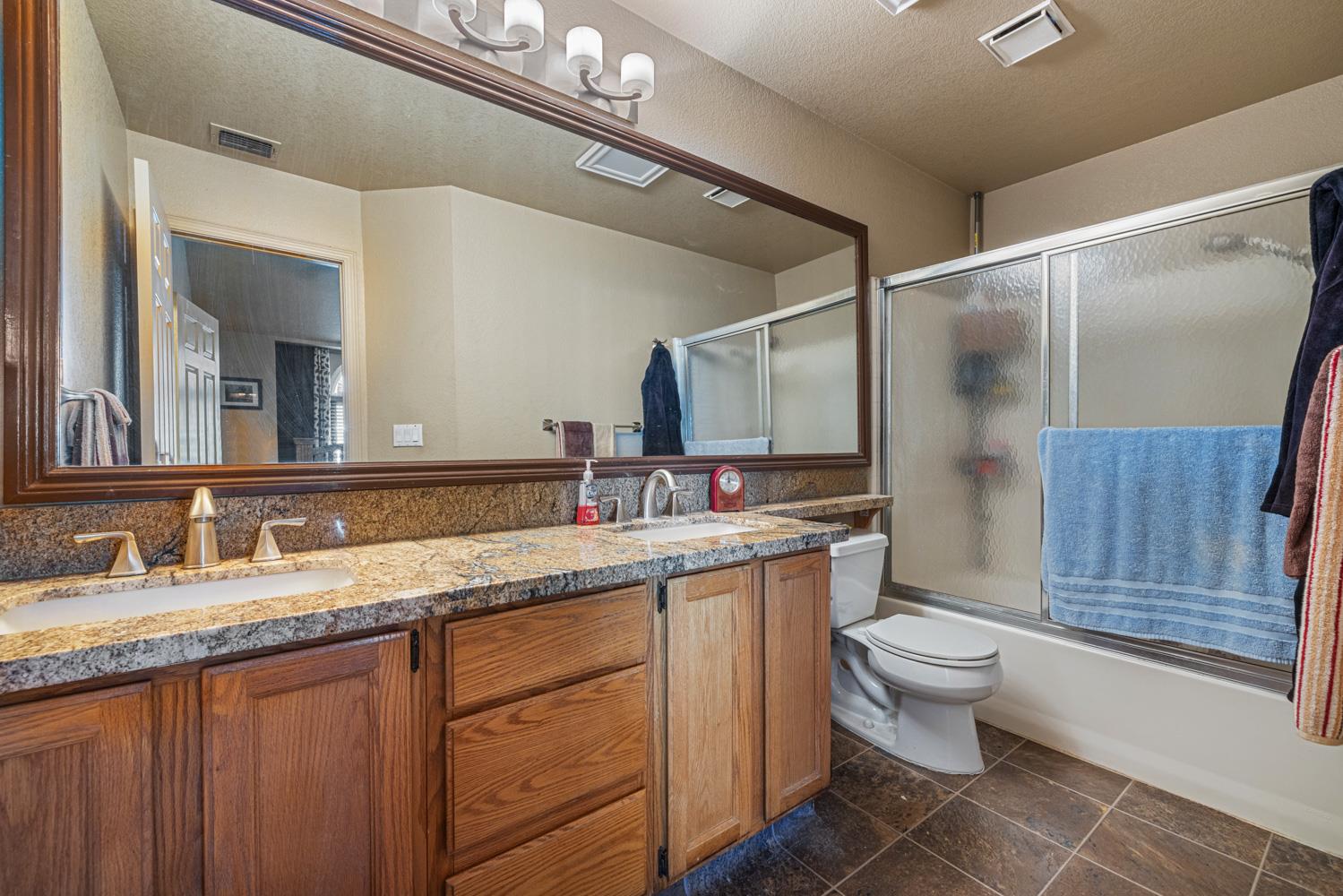 2812 Stone Terrace Modesto, CA 95355 - Photo 27 of 33 a bathroom with a granite countertop sink a toilet and a mirror