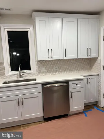 a kitchen with white cabinets and sink