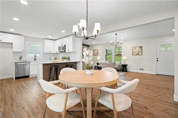 a view of a dining room and livingroom furniture wooden floor a chandelier and a view