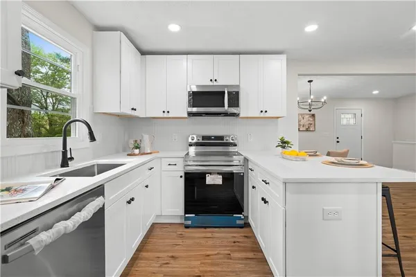 a kitchen with stainless steel appliances a sink a stove and white cabinets