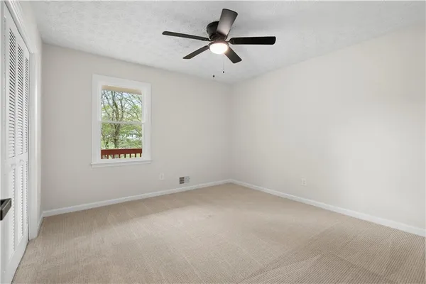 an empty room with a window and a fan