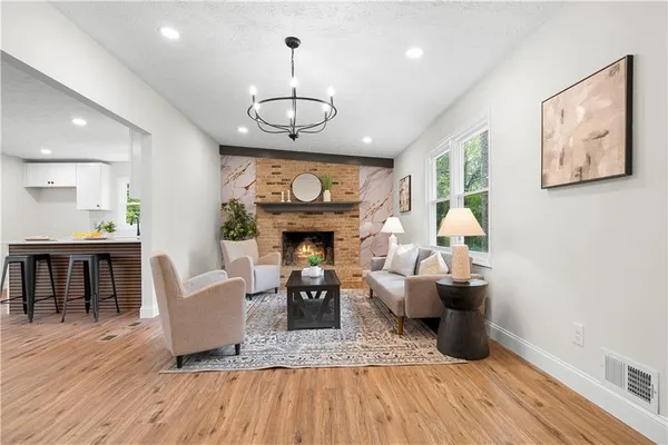 a view of a livingroom with furniture a fireplace wooden floor and chandelier