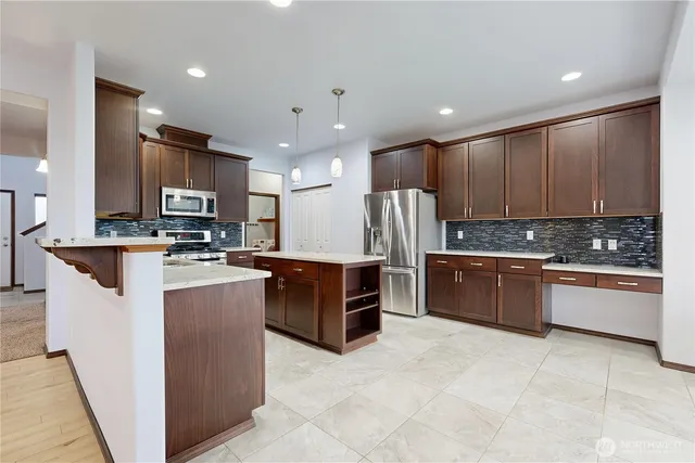 a kitchen with stainless steel appliances granite countertop a refrigerator a stove a sink and a microwave