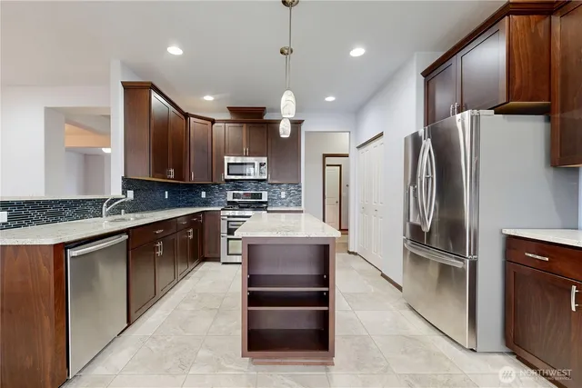 a kitchen with stainless steel appliances granite countertop a refrigerator and a stove top oven